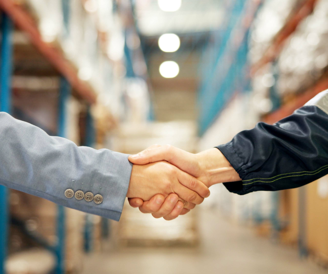 Two people shaking hands in a warehouse